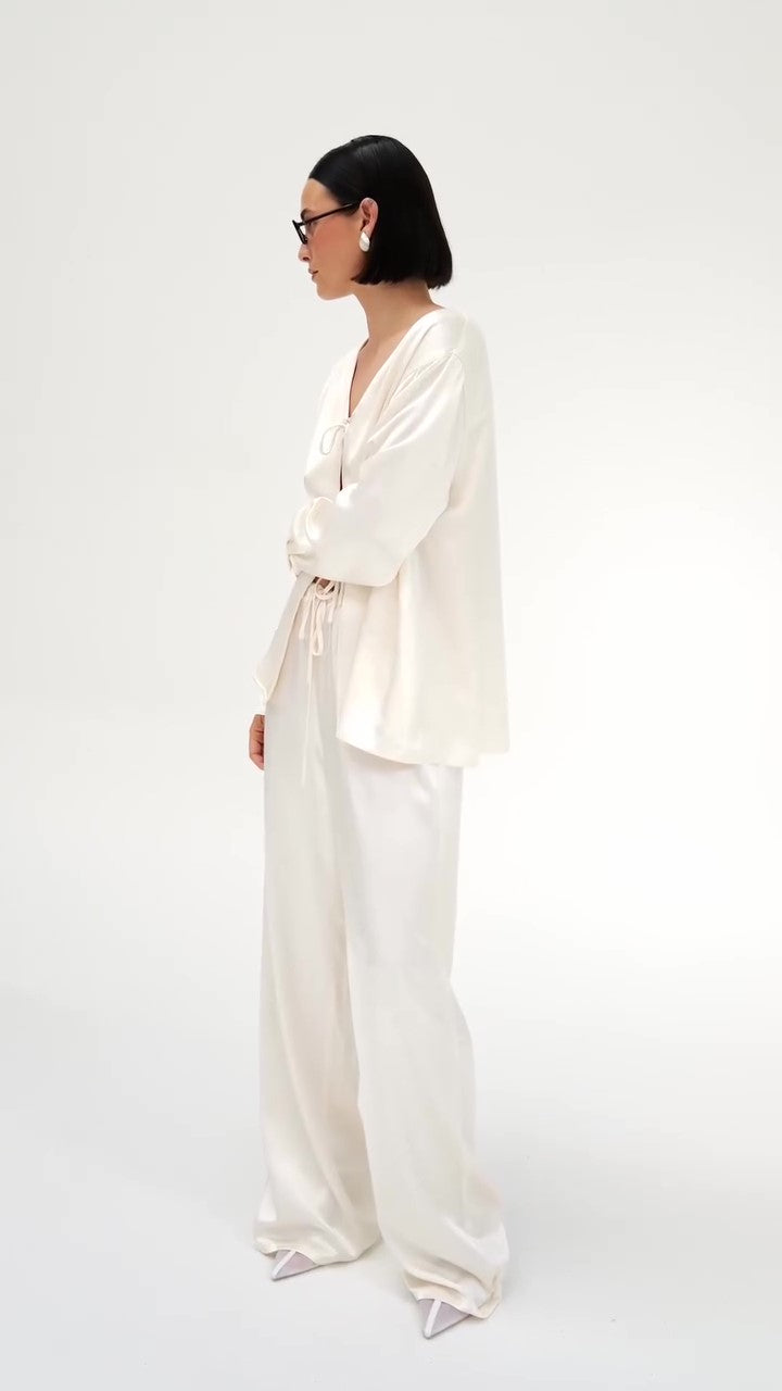 क्रीम रंग का सैटिन टाई-फ्रंट टॉप और वाइड-लेग पैंट का सेट