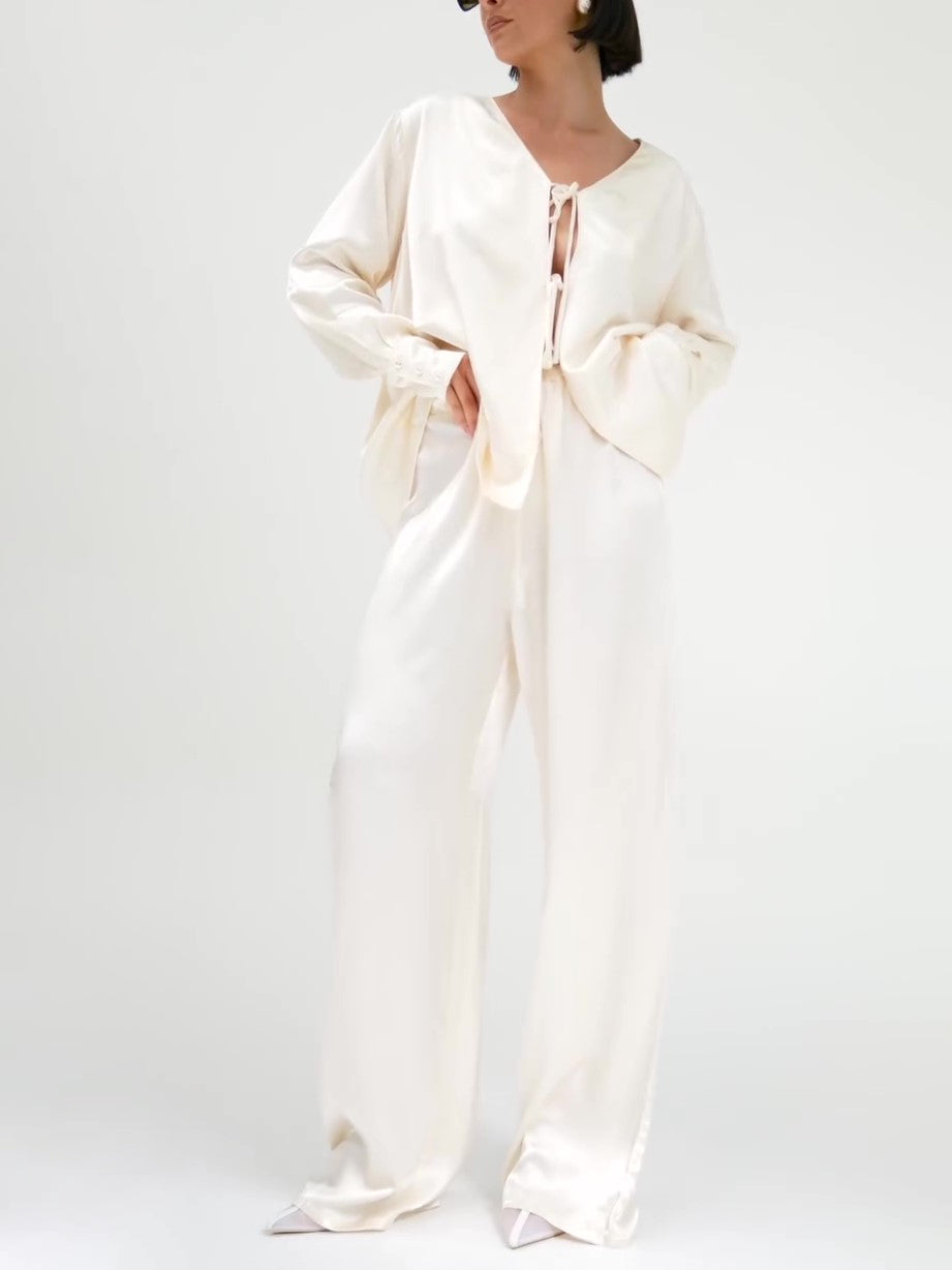 क्रीम रंग का सैटिन टाई-फ्रंट टॉप और वाइड-लेग पैंट का सेट